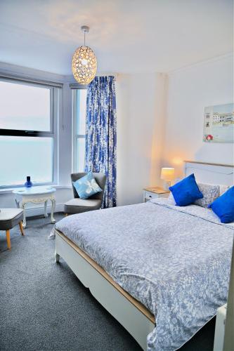 クリクキエスにあるBay View, Sleeps 18, 7 Bedrooms, 7 Bathrooms, Seafront, Cricciethのベッドと椅子と窓のある寝室