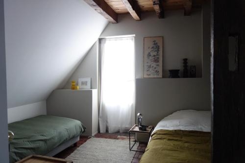 een slaapkamer met 2 bedden en een raam bij la maison haute in Toucy