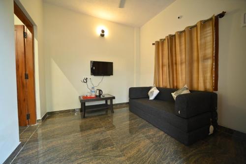a living room with a black couch and a tv at Coorg HomeStay Resort in Kushālnagar