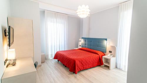a white bedroom with a red bed and a chandelier at Bobby Executive in Sanremo