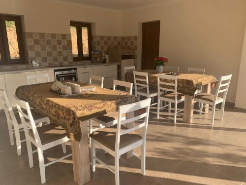 ein Esszimmer mit 2 Tischen und Stühlen sowie eine Küche in der Unterkunft Vitál Guesthouse in Almamellék