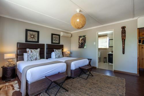 a bedroom with two beds and a chandelier at Inverdoorn Game Reserve Lodge in Breede River DC
