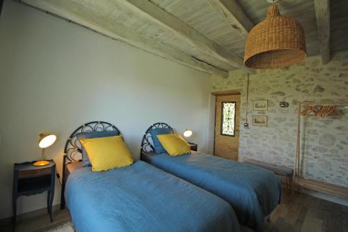 a bedroom with two beds with blue sheets and yellow pillows at La cle des champs 