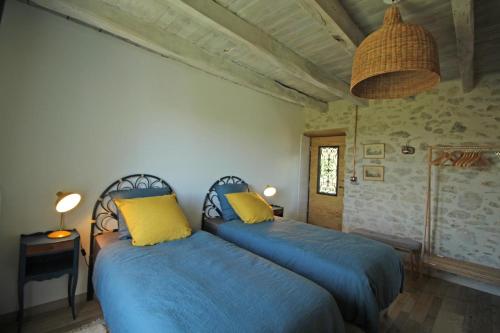 a bedroom with two beds with blue sheets and yellow pillows at La cle des champs in Saint-Victurnien