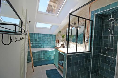 a bathroom with blue tiles and a shower and a sink at La cle des champs 