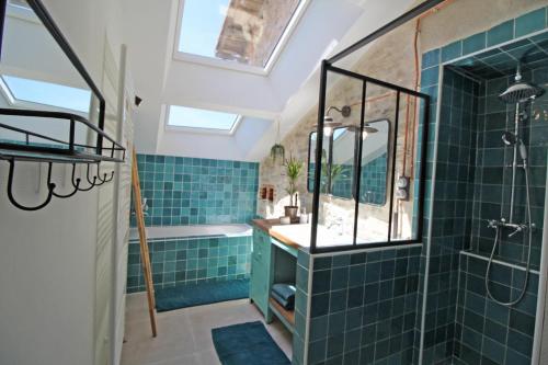 a bathroom with blue tiles and a shower and a sink at La cle des champs in Saint-Victurnien