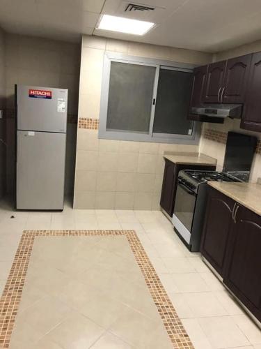 a kitchen with brown cabinets and a refrigerator at SN Realestate Resedent in Abu Dhabi