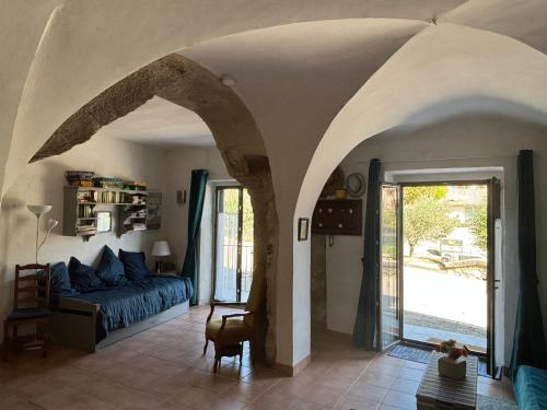 una sala de estar con un sofá azul y un arco en Luberon maison de village entière 2 à 6 personnes, en Cabrières-dʼAigues