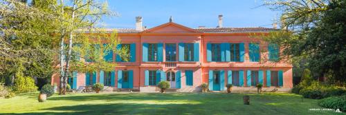 a large house with blue windows and a yard at Chateau Pont Saint-Martin in Léognan