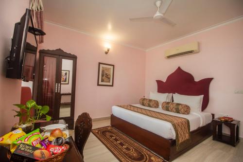 a bedroom with a bed and a television and a table at Amritara Suryauday Haveli in Varanasi