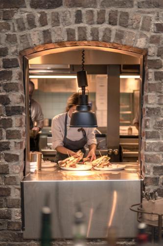 a woman in a kitchen preparing food in a kitchen at GamlaVærket Gjæstgiveri og Tracteringssted in Sandnes