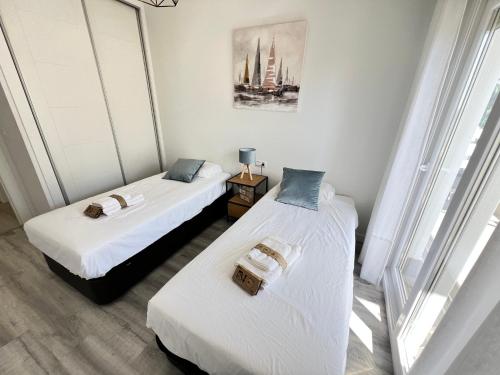 two beds in a room with white walls at PUSHE Playa Granada Beach&Golf 3 in Motril