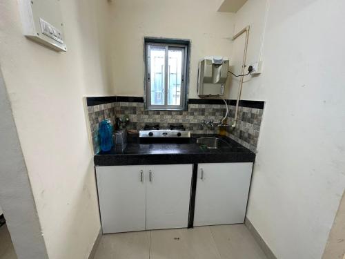 uma pequena cozinha com um lavatório e uma janela em 1BR Apartment Parel em Mumbai