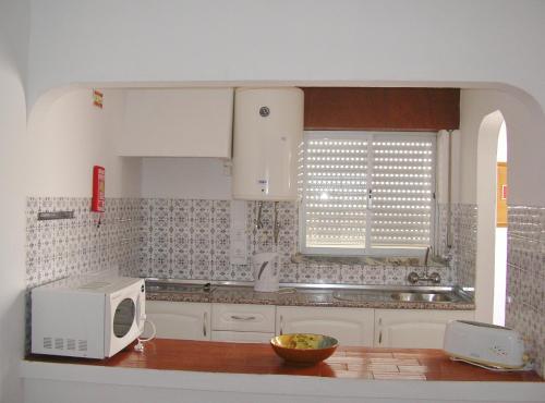 a kitchen with a microwave and a counter top at Apartamentos Salema Praia Club in Salema