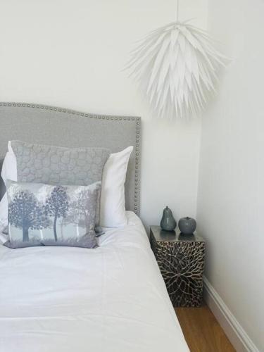 a bedroom with a white bed with a tree pillow at Chelston Grange Torquay Near the Beach with Private Garden & Parking in Torquay