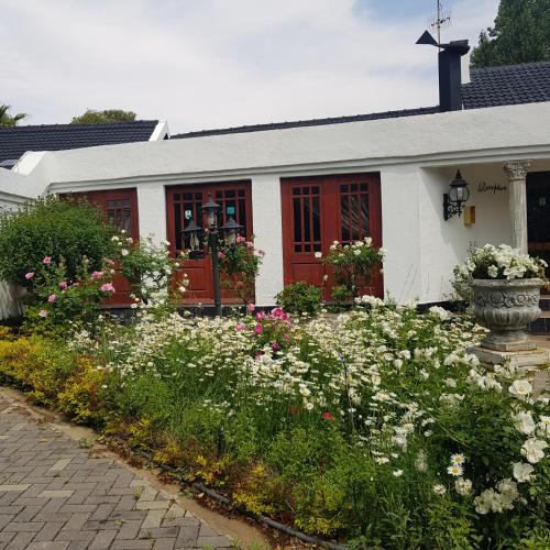 a white house with a red door and some flowers at Lamon Guesthouse in Kroonstad