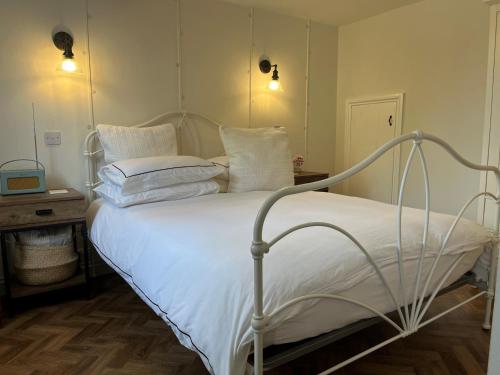ドーチェスターにあるThe Coach House at Lackington Farmの寝室にある白いシーツと枕が置かれたベッド