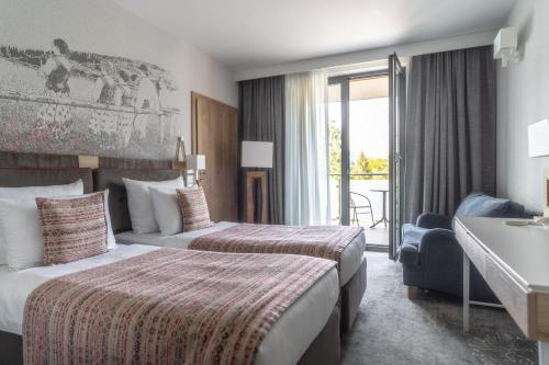 ザコパネにあるHotel Aquarion Family & Friendsのベッド2台とバルコニーが備わるホテルルームです。