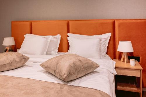una camera con 2 letti con cuscini bianchi e 2 lampade di La Boheme Therme a Ostratu