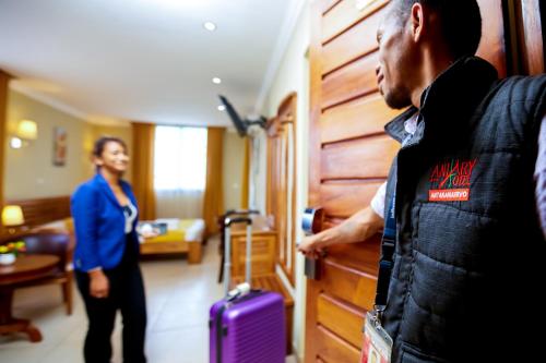 Un homme ouvre la porte à une femme avec une valise dans l'établissement Anjary Hotel, à Antananarivo