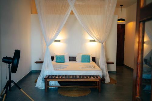 a bedroom with a bed with curtains and a camera at Savera Beach Houses in Jambiani