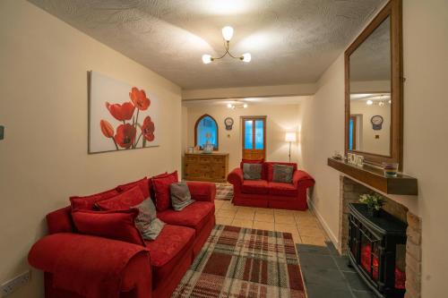 un soggiorno con 2 divani rossi e un camino di Waterfall Cottage a Carnlough