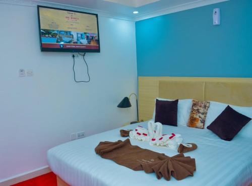 a bedroom with a bed with a tv on the wall at DHE Jomels Hotel in Busia