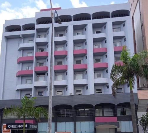 een hoog wit gebouw met rode en roze ramen bij Gree Hotel in São Luís