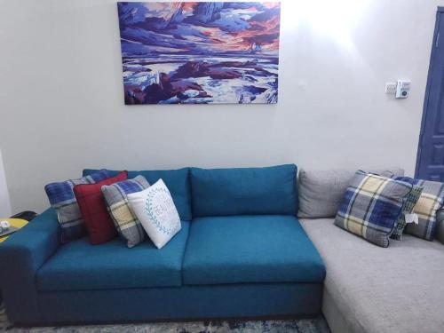 a blue couch with pillows and a painting on the wall at Apartments for short stay in Ashalebotwe