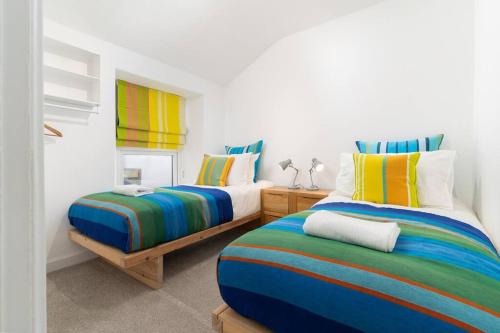 - une chambre avec 2 lits avec des draps rayés colorés dans l'établissement Beautiful and Contemporary Cornish townhouse in Penzance, à Penzance