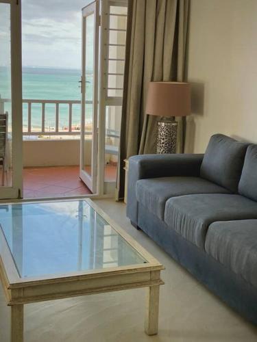 a living room with a blue couch and a glass table at Dolphins Stay in Summerstrand
