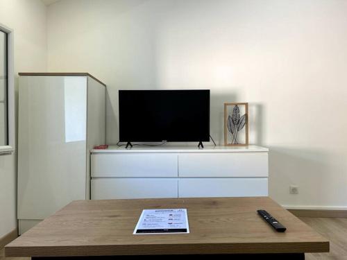 a living room with a tv on top of a dresser at Studio rénové centre-ville de Lagnieu / WIFI in Lagnieu