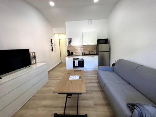 a living room with a couch and a table at Studio rénové centre-ville de Lagnieu / WIFI in Lagnieu