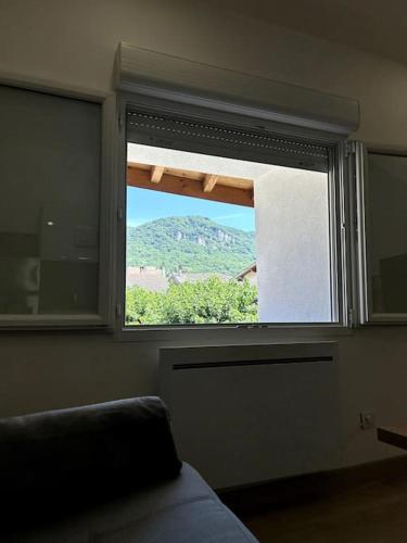 une fenêtre dans une pièce avec vue sur une montagne dans l'établissement Studio rénové centre-ville de Lagnieu / WIFI, à Lagnieu