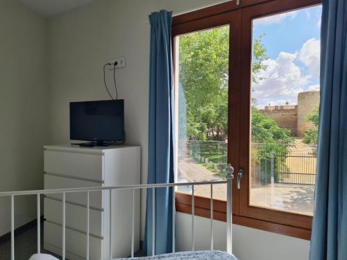 Zimmer mit einem Fenster, einem TV und einem Balkon. in der Unterkunft Casa Xanadu Carmona - Apartments in villa with panoramic views in Carmona