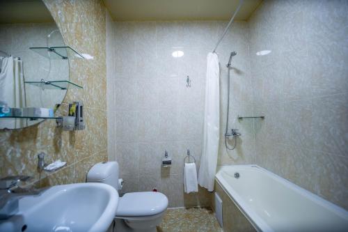 a bathroom with a toilet and a sink and a tub at Reikartz Modarixon Bukhara in Bukhara