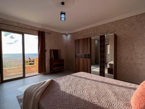 a bedroom with a bed and a view of the ocean at Villa Sunset Moulay Bouzerktoun in Essaouira