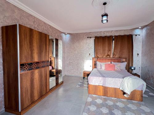 a bedroom with a bed with a wooden headboard at Villa Sunset Moulay Bouzerktoun in Essaouira