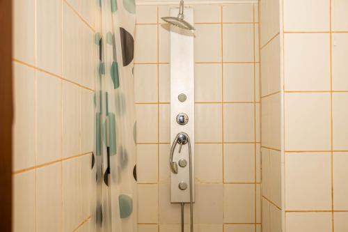 a shower with a white tiled wall with a shower head at Occidental Wise Transit Hotel in Bucharest