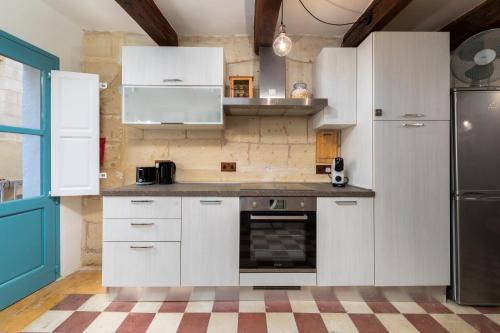 a kitchen with white cabinets and a refrigerator at Traditional Maltese Townhouse - Close to Sea in Senglea