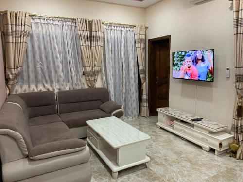 ein Wohnzimmer mit einem Sofa und einem Flachbild-TV in der Unterkunft Coyimo in Ouagadougou