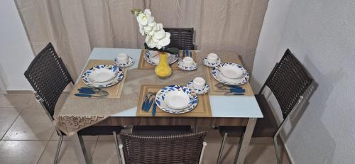- une table avec de la vaisselle et un vase de fleurs dans l'établissement Pedacinho de Lar, à João Pessoa