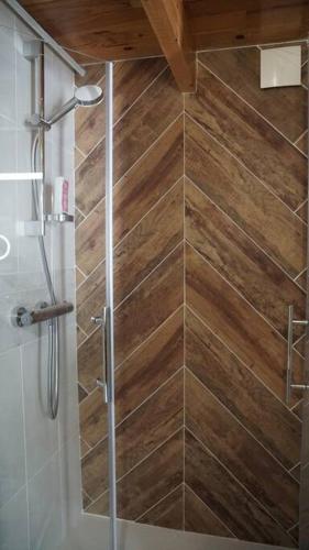 La salle de bains est pourvue d'une douche et d'un mur en bois. dans l'établissement Gîte Coco Studio à 20 km de Saumur, à Vernoil