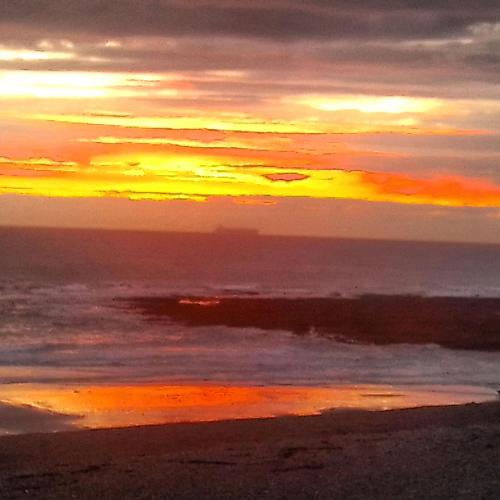 einen Sonnenuntergang am Strand mit dem Meer in der Unterkunft Sundown in Audresselles