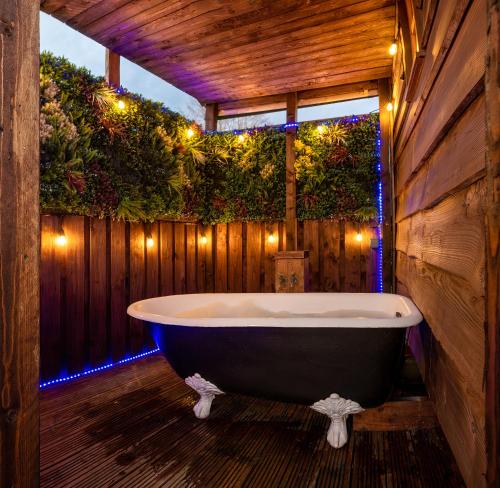 a bath tub in a bathroom with a wooden wall at The Shepherds Retreat - Ockeridge Rural Retreats in Wichenford