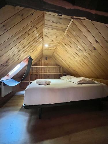 un lit dans une chambre avec un plafond en bois dans l'établissement Le petit Verdun, à Saint-Aignan