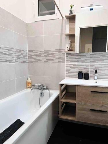 une salle de bain avec une baignoire et un lavabo et une baignoire dans l'établissement Logement entier chambre+salon + jardin & terrasse, aux Ulis