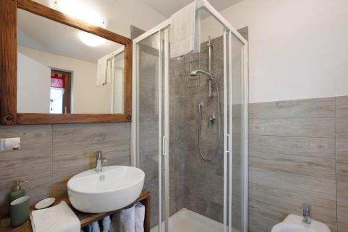 uma casa de banho com um chuveiro, um lavatório e um espelho. em La Vigne De Papagran App1 em Aosta
