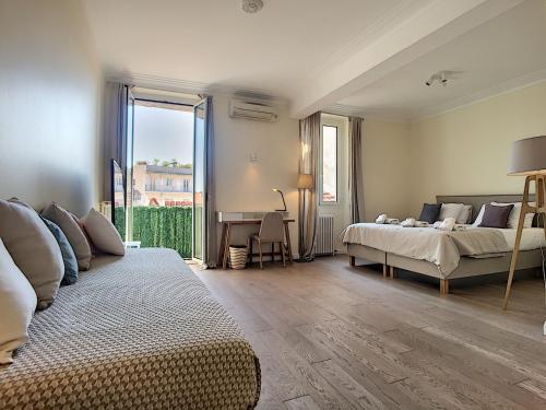 1 Schlafzimmer mit 2 Betten, einem Schreibtisch und einem Tisch in der Unterkunft Nestor&Jeeves - PALAIS MASSENA - pedestrian street, very close sea in Nizza