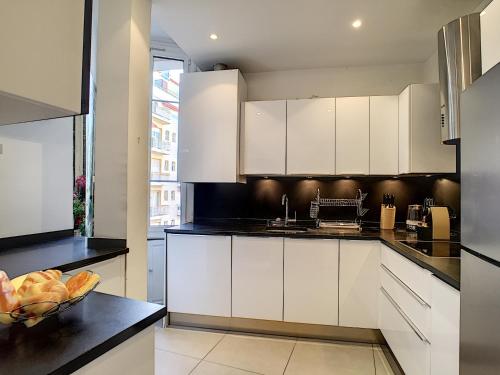 une cuisine avec des armoires blanches et un bol de fruits sur un comptoir dans l'établissement Nestor&Jeeves - PALAZZO VERDI - Central, à Nice